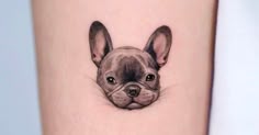 a small tattoo of a dog's face on the leg, with an ear