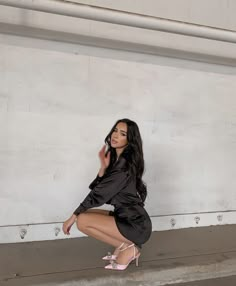 a woman kneeling down on the ground with her hand up to her face and wearing high heels