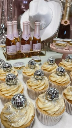 some cupcakes are sitting on a table with champagne bottles in the back ground