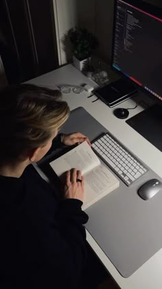 a person sitting at a desk with a book and computer