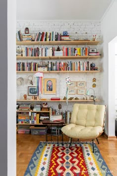 a living room filled with lots of books and furniture next to a white brick wall