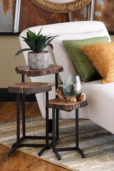 two end tables with plants on them in front of a white couch and rugs