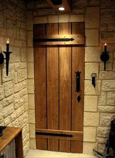 a wooden door sitting inside of a stone wall next to a table and lamp holders