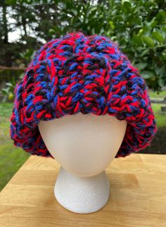 a white mannequin head wearing a red, blue and black knitted hat