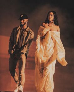 a man standing next to a woman in a white dress on top of a stage