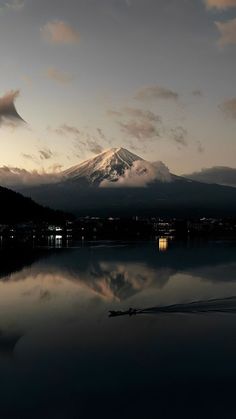 a boat is on the water in front of a snow covered mountain at night time