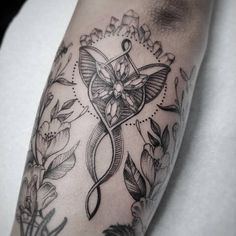 a black and white photo of a tattoo design on the arm, with flowers around it