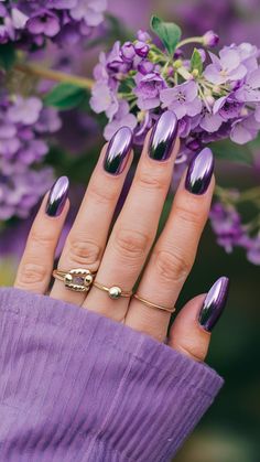 This stunning image showcases a striking set of purple chrome nails that shimmer beautifully, set against a backdrop of delicate flowers. The nails feature a glossy, reflective finish that enhances their vibrant hue, creating a captivating look that draws the eye. This nail design is perfect for fashion enthusiasts and anyone looking to make a statement during spring events or special occasions. To complete the look, consider pairing these nails... Beautiful Manicure Ideas, Purple Nails Different Shades, Bright Lilac Nails, Purple Nail Polish Designs, Purple Holographic Nails Designs, Purple Black Nails Designs, Classy Nails Purple, Purple Mirror Nails, Purple Chrome Nails Short