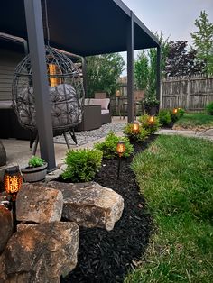 an outdoor patio with rocks and lights in the grass next to a gazebo that is lit up