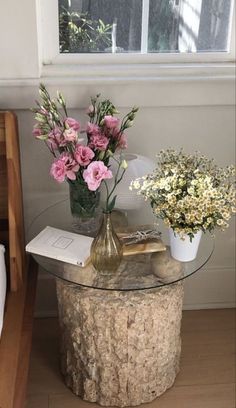 a glass table with flowers on it in front of a window