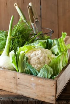 a wooden crate filled with lots of green vegetables