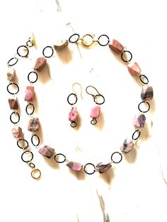 I handcrafted this unique set of three items from 100% large natural rhodonite with a modern cut and black-colored steel hardware.  The short necklace, measuring 40 cm, combines the femininity of rhodonite with the boldness of black rings.  The necklace features a spring ring clasp, completing the composition of pink, black, and gold colors.  The bracelet has a toggle clasp and an extension chain for easy fastening.  The earrings have stainless steel ear wires. The set is hypoallergenic and envi Unique Pink Gemstone Beads Jewelry, Artisan Pink Gemstone Beads Jewelry, Pink Tourmaline Bohemian Jewelry, Handmade Pink Jewelry For Gifts, Pink Round Jewelry With Gemstone Beads, Pink Round Gemstone Beads Jewelry, Round Pink Jewelry With Gemstone Beads, Pink Gemstone Jewelry For Jewelry Making, Pink Round Gemstone Beaded Jewelry