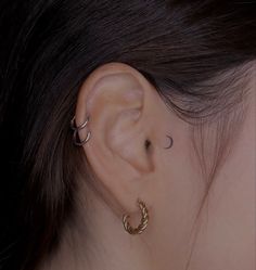 a woman's ear with two small hoops on the side of her ear