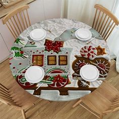 the table is set for christmas dinner with white plates and silverware, along with two wooden chairs