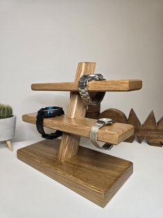 a wooden stand with rings and bracelets on it next to a potted cactus