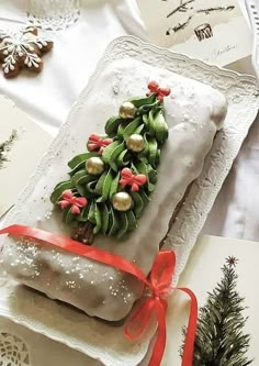 a white plate topped with a pastry covered in icing next to a christmas tree