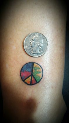 a half dollar coin sitting on top of a woman's shoulder with colorful tattoos