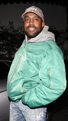 a man in a green jacket is standing next to a car