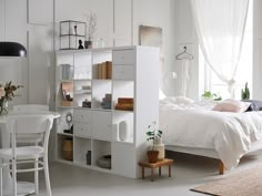 a bedroom with white walls and furniture in it, including a bed that's surrounded by bookshelves