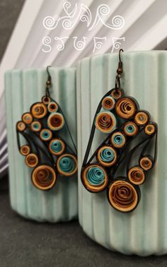 two pairs of earrings with spiral designs on them sitting next to each other in front of a book