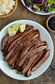 a plate with steak, rice and salad on it next to a bowl of black beans