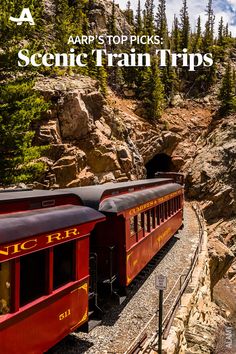 a red train traveling through a lush green forest covered hillside next to a rocky cliff