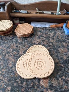 three wooden coasters sitting on top of a granite counter next to other woodworking tools