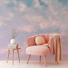 a pink chair next to a small table with a vase on it and a sky background