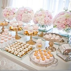 a table topped with lots of desserts next to a vase filled with pink flowers