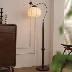 a lamp that is on top of a wooden floor next to a chair and table