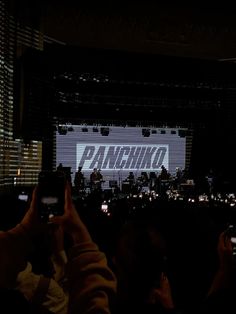 people are taking pictures with their cell phones in front of a large screen that says panshiko