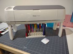 a printer sitting on top of a table next to a pile of colored pens and pencils