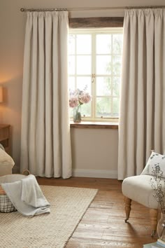 a living room filled with furniture and a window covered in white drapes next to a wooden floor