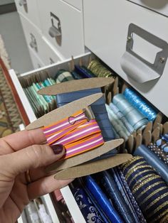 a hand holding an open shoe box in front of a file cabinet filled with ties