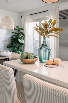 a dining room table with two chairs and a bowl of succulents