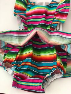 Perfect for all the summer 🥳 FIESTAS!! Handmade skirt romper. Made with cotton serape cotton fabric. These amazing pieces are made to order. Sizes 0-6 month up to 4T are made with attached bloomers and snaps at the saddle. Anything above a 4t (5t -7/8y) are the same style dress with no bloomers attached. If you have any questions on sizing please don't hesitate to message me. I will gladly help. Rainbow Cotton Dress For Playtime, Rainbow Cotton Playtime Dress, Cotton Ruffle Dress For Festivals, Cotton Ruffled Dress For Festivals, Cotton Festival Dress With Ruffles, Rainbow Summer Dress For Playtime, Rainbow Summer Dresses For Playtime, Summer Rainbow Playtime Dress, Playful Rainbow Cotton Dresses