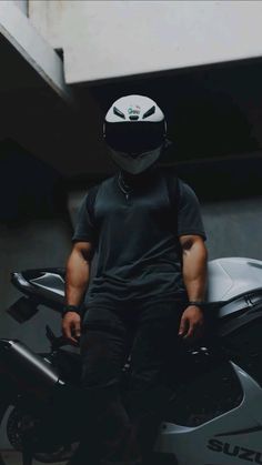 a man sitting on the back of a motorcycle wearing a helmet and black sweatpants