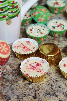 some cupcakes sitting on top of a counter next to a coffee mug and christmas decorations