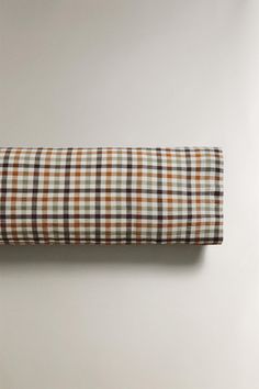 an orange and brown checkered pillow on a white wall