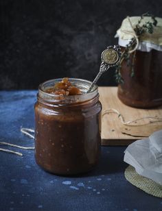 a jar filled with food sitting on top of a wooden table next to a cutting board