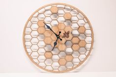 a wooden clock with hexagonal design on the face and hands is shown in front of a white wall