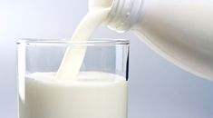 a glass filled with milk being poured into it