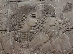 an ancient relief depicting two women with headscarves on their backs, possibly from egypt