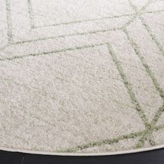 a white rug with green lines on the top and bottom, sitting on a wooden floor