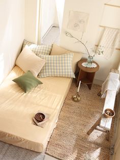 a small bedroom with a single bed and pillows on the bottom floor, next to a window