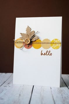 a white card with yellow and brown leaves on it that says hello written in gold