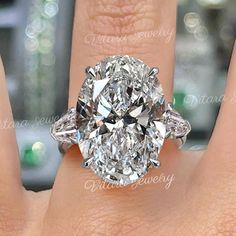 a close up of a person's hand with a diamond ring on their finger