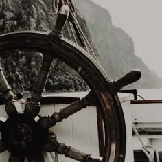 the steering wheel of a ship with mountains in the background