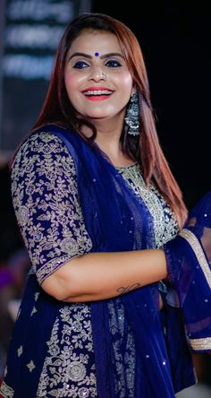 a woman in a blue sari is smiling at the camera