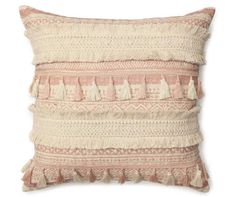 a pink and white pillow with tasselled fringes on the front, sitting on a white surface